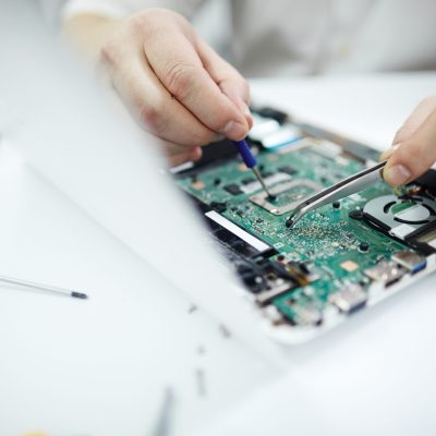 Closeup of Fixing Disassembled Laptop Closeup shot of male hands repairing parts in disassembled laptop using screwdriver and different tools on table in workshop